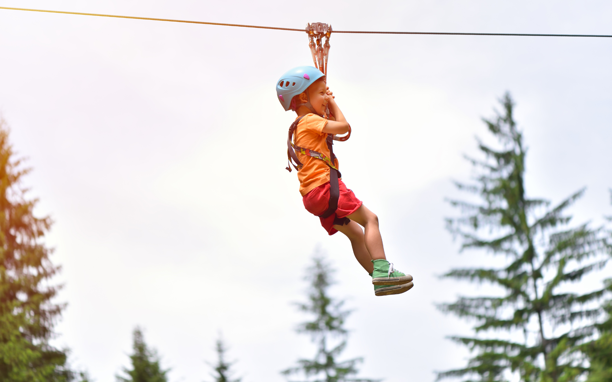 Little kids ziplining through the woods